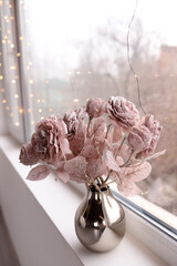 Artificial rose flowers in vase on the windowsill. Vertical orientation