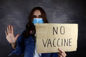 young woman in a medical mask with a cardboard with the inscription No vaccine, stop vaccine concept