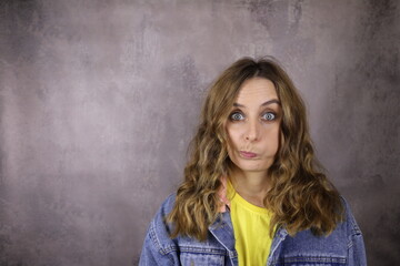 Young woman with an unhappy grimace on a gray background