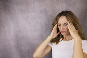 young woman suffering from a migraine headache , holding her temples