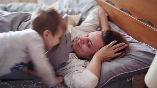 A beautiful girl and her son kisses her in bed