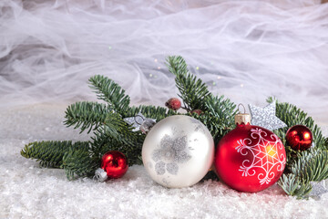 Christmas balls and fir branches on a blurred white background. Blur and selective focus