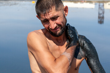 A man smears his body with healing mud. Salty, mud medicinal lakes of Sol-Iletsk.