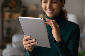 Crop close up of smiling Latino woman use tablet gadget talk speak on webcam call online. Happy Hispanic female hold pad device browse wireless internet or shop on web. Communication concept.