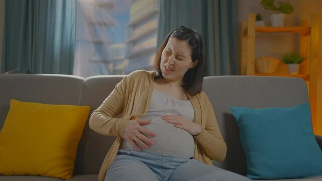 pregnant woman sitting on the couch having labor contractions pain