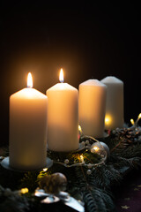 Obraz na płótnie Canvas Fourth advent, four candles - candlelight on dark brown panorama background - advent banner. Horizontal banner for homepage. Template for greeting cards, funeral cards and obituaries.