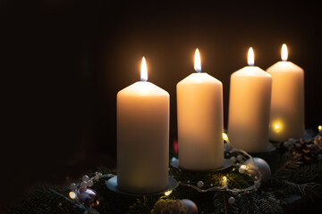 Obraz na płótnie Canvas Fourth advent, four candles - candlelight on dark brown panorama background - advent banner. Horizontal banner for homepage. Template for greeting cards, funeral cards and obituaries.
