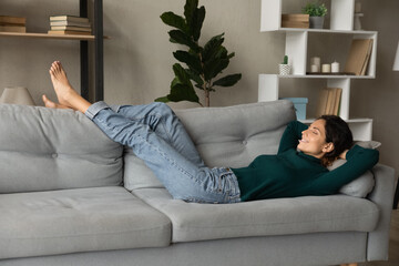 Peaceful hispanic woman relax rest on comfortable couch at home sleep or daydream with eyes closed....