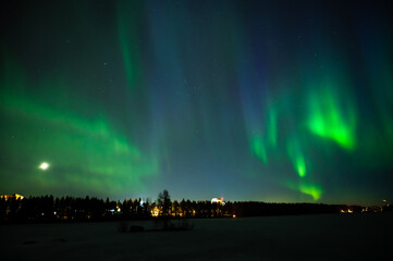 A multi colour geomagnetic Northern Lights on the starry night sky over a city. Aurora Borealis over Swedish lake Islands. Northern Sweden.