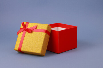 Red gift box with bow and yellow lid on blue background.
