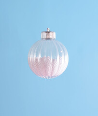 Transparent Christmas ball, pastel blue background. Minimal winter concept. 