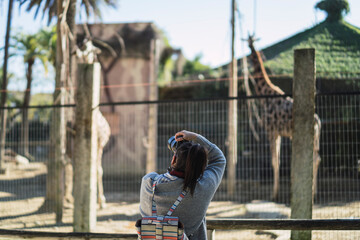 Chica joven de espaldas realizando fotografías en el zoologico