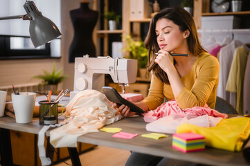 Young entrepreneur woman working in her small workshop, calculating expenses, making business plan
