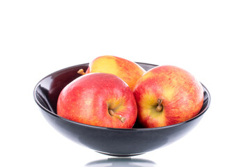 Three juicy red apples on a ceramic plate, close-up, isolated on white.