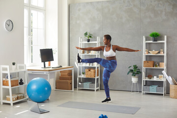Happy black woman having sports workout at home. Active young lady standing in living room,...