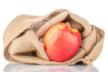 One juicy red apple with a jute bag, close-up, isolated on white.
