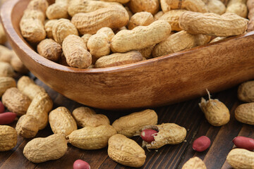 Raw organic peanuts in a wooden bowl.