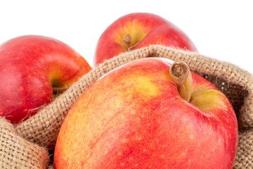 Three juicy red apples with a jute bag, close-up, isolated on white.