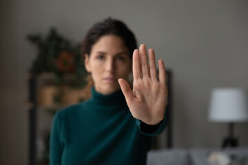 Crop close up of young Latino woman show no palm stop hand gesture against racial or gender...