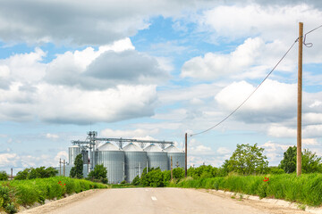 Obraz premium Road to Silos on a beautiful day with puffy clouds and fresh green grass