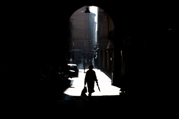 Silhouette of a lady walking in the alleys of Bologna, in Italy.

