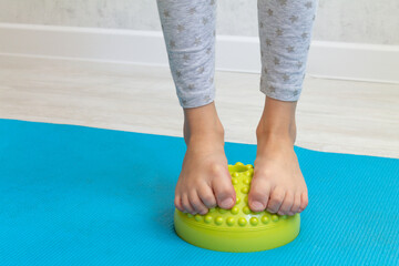 The child performs exercises on the green balancer from the valgus of the foot. The child's legs...