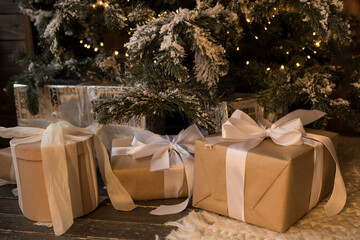 Obraz premium Christmas background with gift boxes from kraft paper on the background of the Christmas tree. Christmas holiday, preparation for the winter holidays, secret Santa.