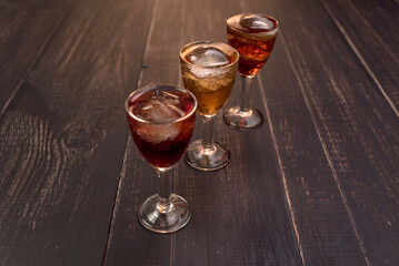 Alcoholic drinks in glass piles on a wooden table. Cherry, nut and lemon liqueurs.