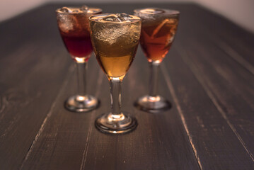 Alcoholic drinks in glass piles on a wooden table. Cherry, nut and lemon liqueurs.