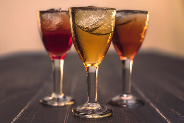 Alcoholic drinks in glass piles on a wooden table. Cherry, nut and lemon liqueurs.