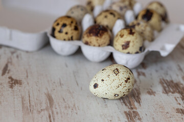 close-up of a quail egg on a wooden table with quail eggs in a box in the background, focus on foreground