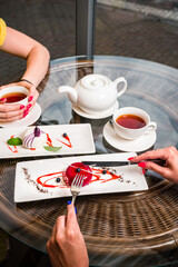 two female friends are eating mousse cakes French dessert and drinking tea in a cafe