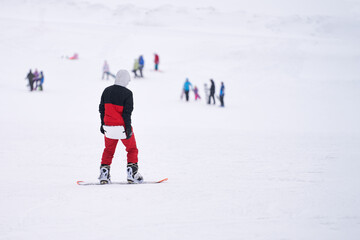 A snowboarder with you (a tourist mat) on his buttocks is standing on a snow-covered mountainside. Copy space.
