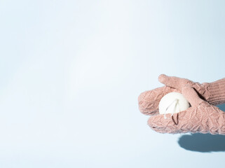 Winter background. Snow ball and mittens. Pastel colors. Light blue and pink.