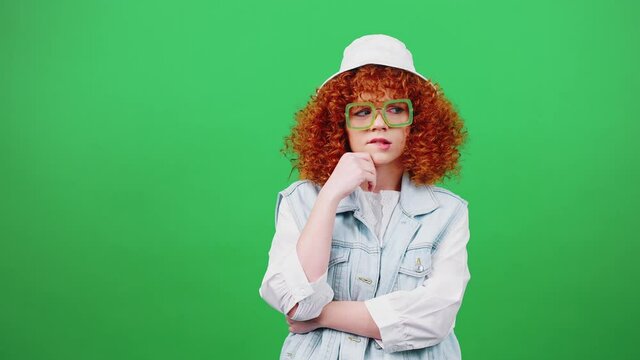 Young pretty redhead woman thinking, having idea and pointing finger up, laughing over green chroma key background