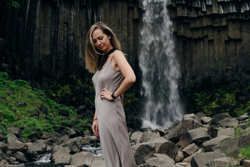 beautiful girl in a dress next to Svartifoss waterfall in the Skaftafell National Park, iceland