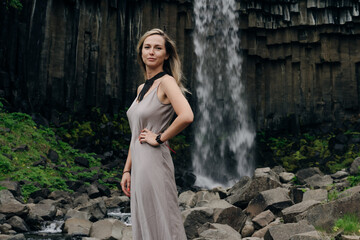 beautiful girl in a dress next to Svartifoss waterfall in the Skaftafell National Park, iceland