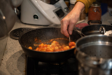 mani che mescolano gnocchi al pomodoro casalinghi in padella