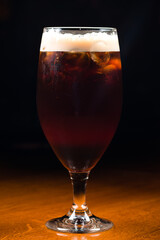 Ice cold glass of dark beer with foam. Stout beer freshly poured