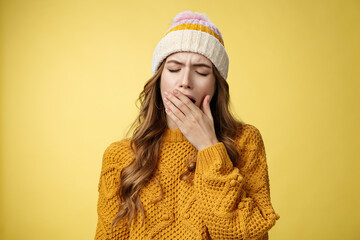 Close-up shot tired yawning cute exhausted european woman wearing hat sweater cover opened mouth feel sleepy drained wanna lay-down take nap, not morning person, yellow background - obrazy, fototapety, plakaty