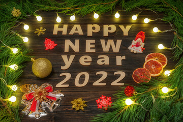 Happy New Year 2022. Various Christmas toys, a bell and a fir tree on a wooden background.