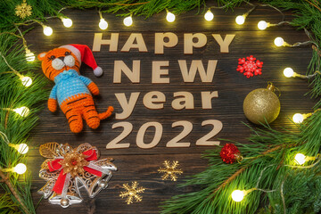 Happy New Year 2022. Christmas toys and a knitted tiger symbol of 2022 on a wooden background.