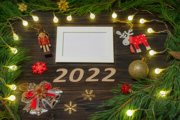 Happy New Year 2022. Christmas toys and a garland on a wooden background with a text frame.