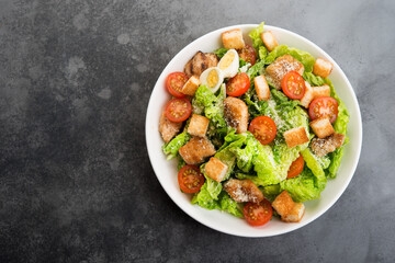 Caesar salad with chicken fillet, cherry tomatoes and croutons, traditional Italian food, top view