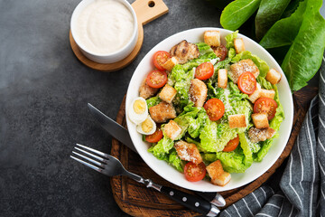 Caesar salad with chicken fillet, cherry tomatoes and croutons, traditional Italian food, top view