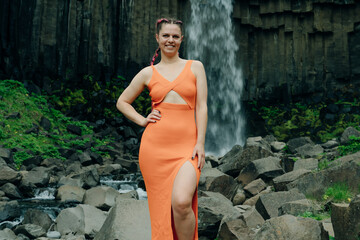 beautiful girl in a dress next to Svartifoss waterfall in the Skaftafell National Park, iceland