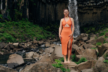 beautiful girl in a dress next to Svartifoss waterfall in the Skaftafell National Park, iceland