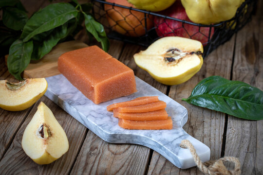 Quince marmalade, with commbert cheese, on a marble board with quince pieces.