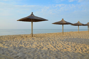 Sandy beach of the sea in the morning in good weather. wooden umbrellas on the beach. a place for...
