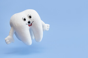 Soft children's toy tooth on a blue background.